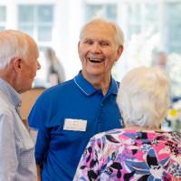 Group of four, two men and two women, standing and  chatting with each other while laughing